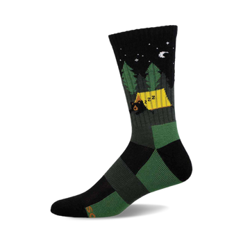 a black and green crew sock with a design of a black bear sleeping in a yellow tent in a green forest at night under a crescent moon.