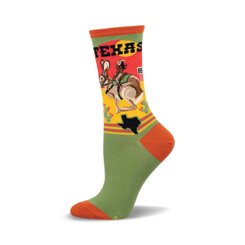 a green sock with an orange toe and heel. the upper part of the sock has a design of a woman riding a jackrabbit with a texas state outline and the word "texas" written on it. the sock is against a white background.