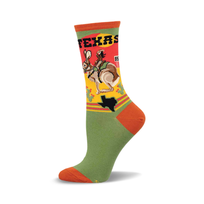 a green sock with an orange toe and heel. the upper part of the sock has a design of a woman riding a jackrabbit with a texas state outline and the word "texas" written on it. the sock is against a white background.