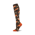 A brown knee-high sock with a repeating pattern of orange foxes and small green leaves. The toe and cuff are a contrasting burnt orange.