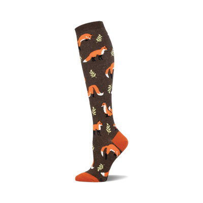A brown knee-high sock with a repeating pattern of orange foxes and small green leaves. The toe and cuff are a contrasting burnt orange.