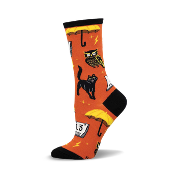 an orange sock with black and yellow designs of owls, cats, umbrellas, and a calendar. the sock is a crew length and has a black toe and heel.