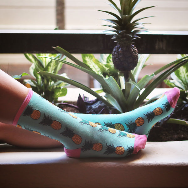 Lifestyle shot of Pineapple Socks on a person's feet near tropical plants. [lf]
