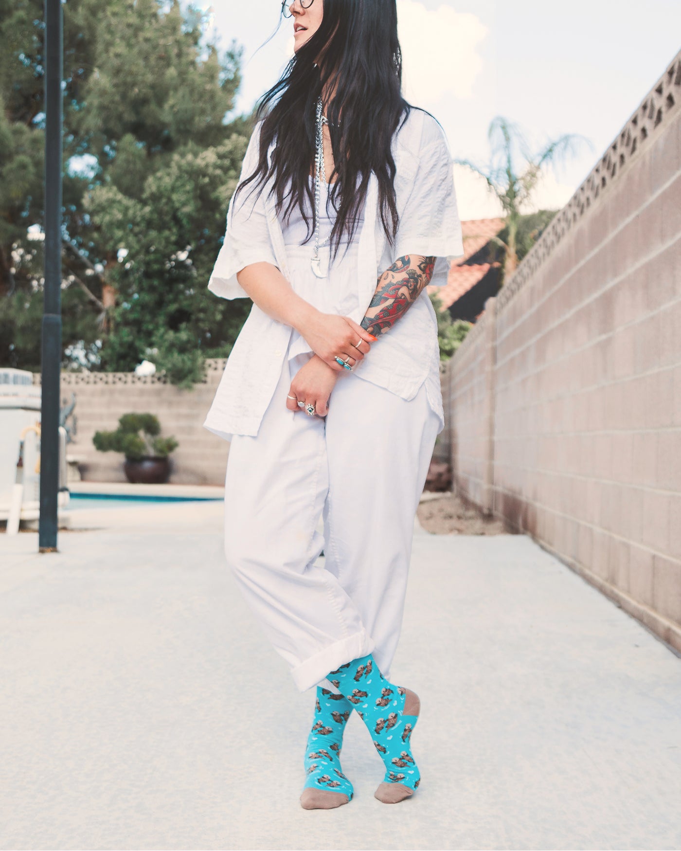 Lifestyle shot: A person with tattoos wearing the teal otter socks with white pants. [lf]