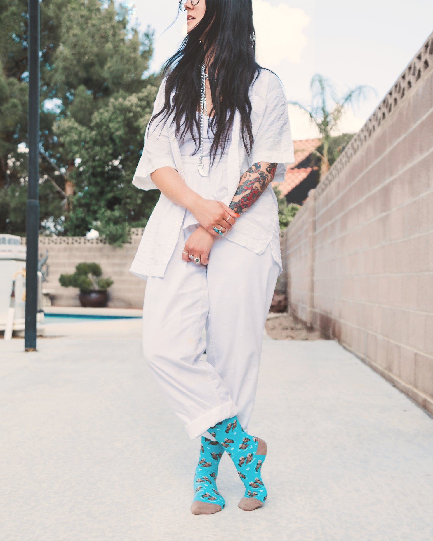 Lifestyle shot: A person with tattoos wearing the teal otter socks with white pants. [lf]