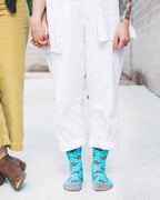 Lifestyle shot: Two people holding hands, one wearing the teal otter socks. [lf]