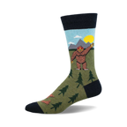 Crew socks in olive green, navy blue, and light blue, featuring a cartoon Bigfoot waving, mountains, and little trees.