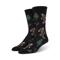 Pair of black Bigfoot XL crew socks. Features repeating pattern of Bigfoot, trees, and footprints. Brown, green, and black design on a black background.