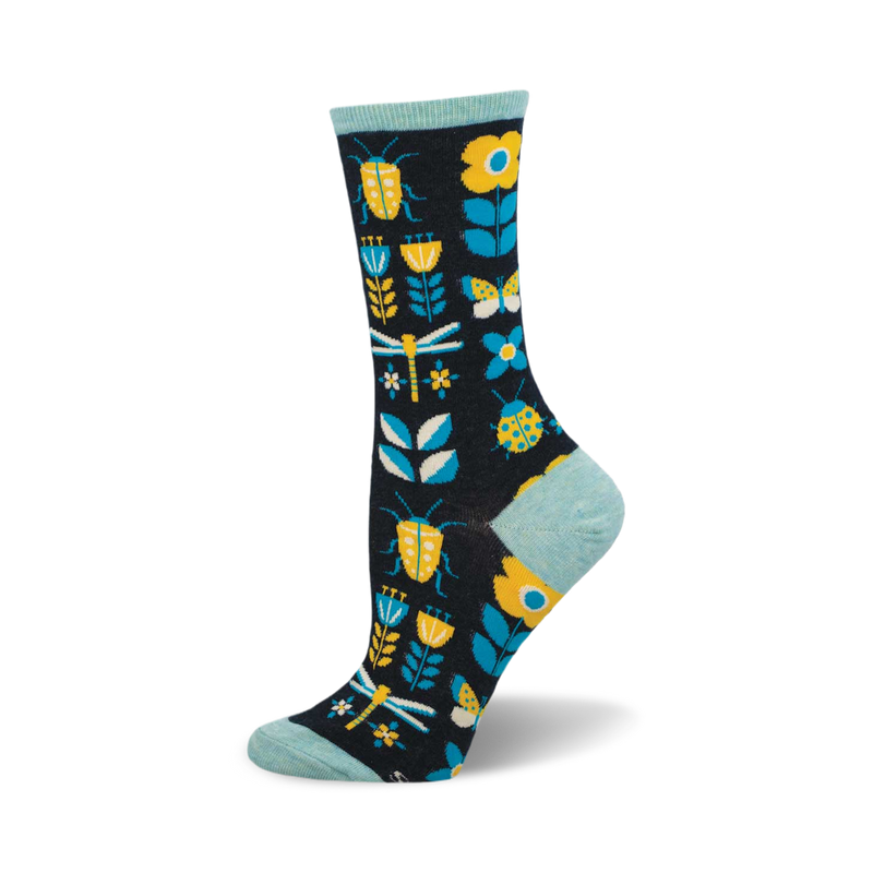 A pair of crew socks in navy blue features yellow ladybugs, dragonflies, butterflies, and flowers on a dark background. The socks have a light teal cuff.