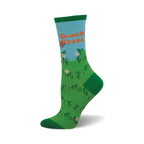 Crew socks in green and light blue, depicting a field of grass, flowers, and a butterfly with the phrase 'Touch Grass'.