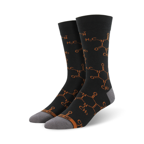 Pair of crew socks in dark grey with a repeating burnt orange caffeine molecule pattern.  The socks have grey heels and toes.