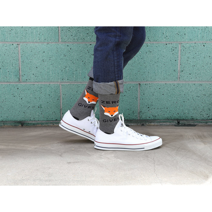 A person is wearing a pair of gray socks with an orange fox face and the words 