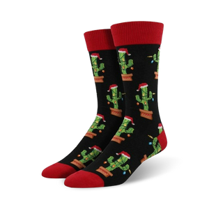 Pair of crew socks; black background with repeating pattern of cacti wearing Santa hats and Christmas lights; red cuffs.
