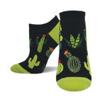 A pair of ankle socks with a black background and a fun pattern of various cacti and succulents in shades of green. The socks have lime green heels and toes.