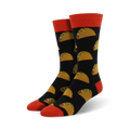 Pair of black crew socks with a repeating pattern of yellow tacos and green toppings. The socks have orange cuffs.