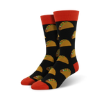 Pair of black crew socks with a repeating pattern of yellow tacos and green toppings. The socks have orange cuffs.