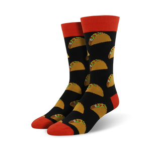 Pair of black crew socks with a repeating pattern of yellow tacos and green toppings. The socks have orange cuffs.