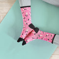 Flatlay product shot of pink yoga socks on a teal yoga mat. [lf]