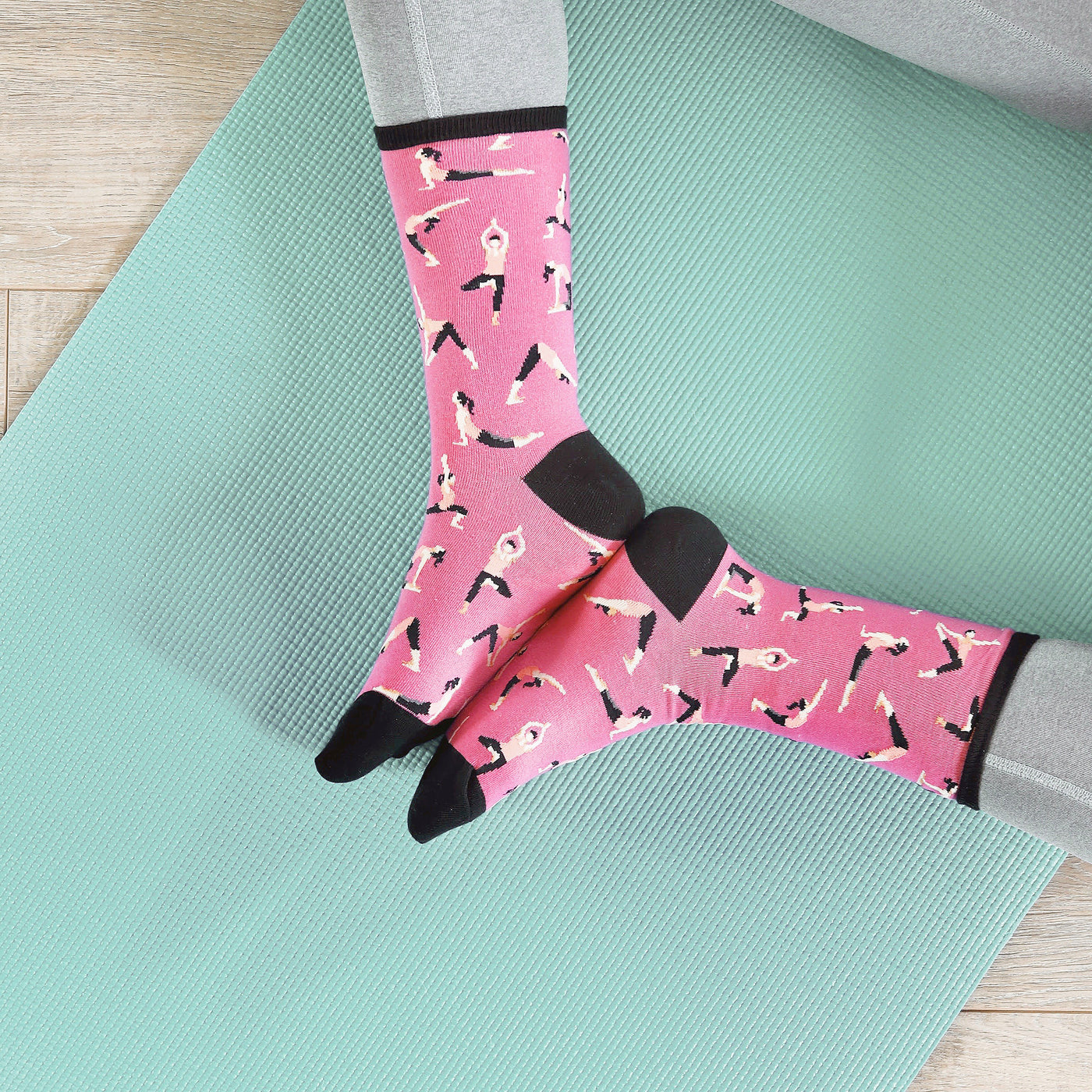 Flatlay product shot of pink yoga socks on a teal yoga mat. [lf]