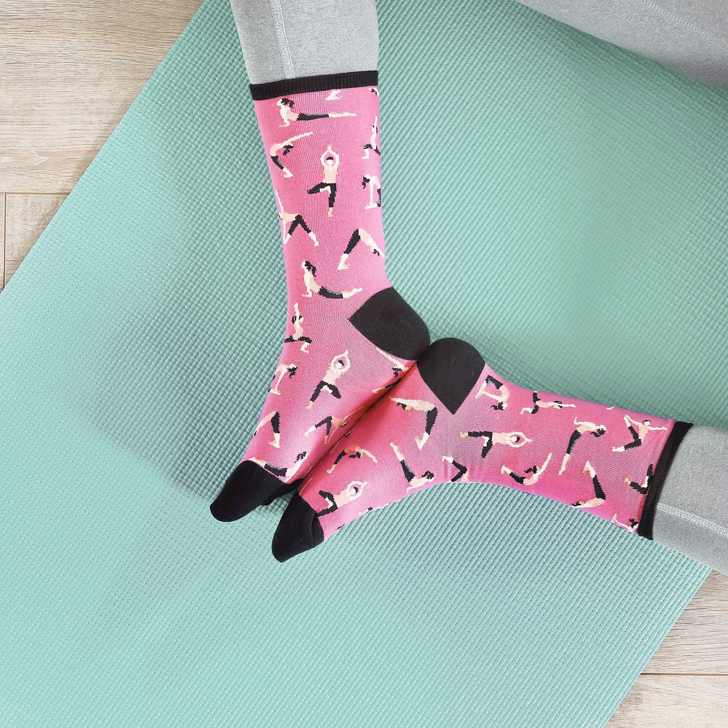Flatlay product shot of pink yoga socks on a teal yoga mat. [lf]