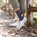 Lifestyle shot of woman's legs wearing the navy blue chicken socks with white canvas shoes. [lf]