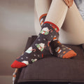 Lifestyle photo showing a person wearing the Cocoa Christmas socks with tan pants. The socks are prominently displayed. [lf]