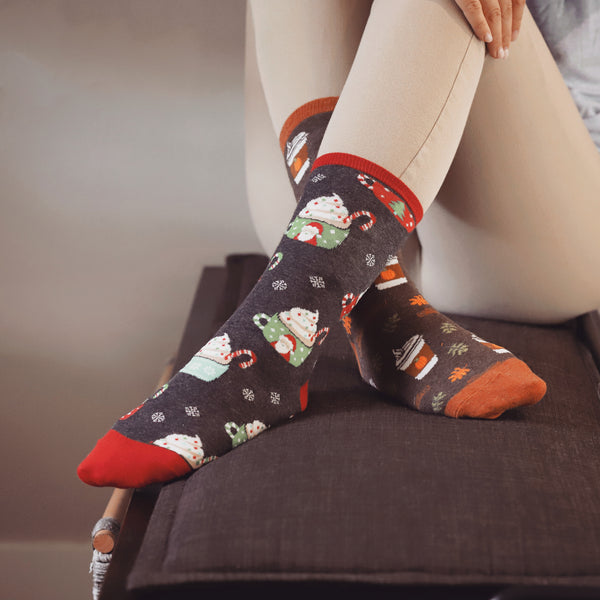 Lifestyle photo showing a person wearing the Cocoa Christmas socks with tan pants. The socks are prominently displayed. [lf]