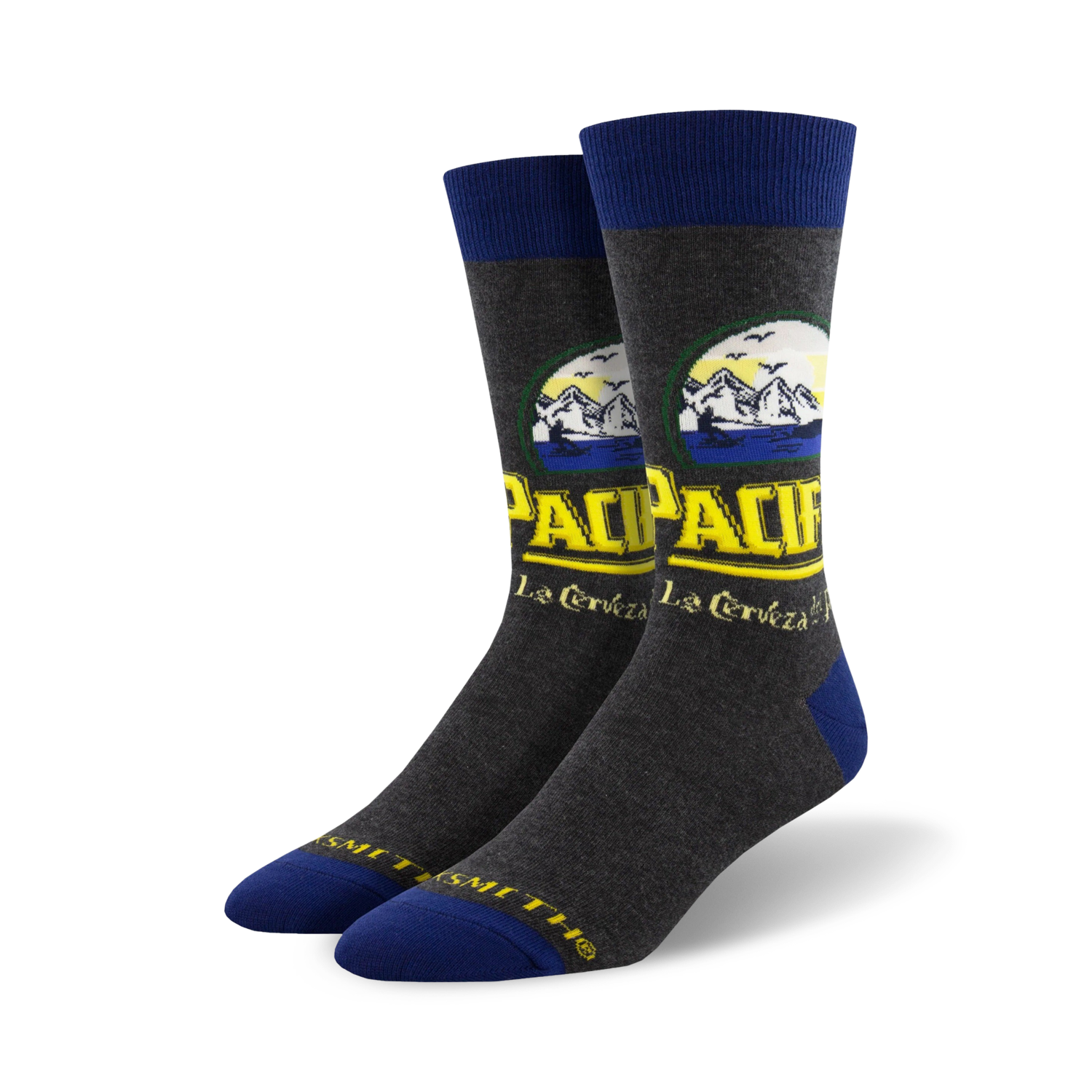 Pair of crew socks in grey with a Pacifico beer-inspired design featuring yellow and blue text and mountain imagery.