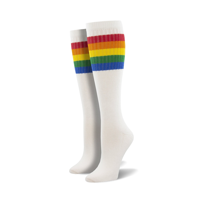 Pair of light blue knee-high socks with a vibrant rainbow striped cuff against a white background.
