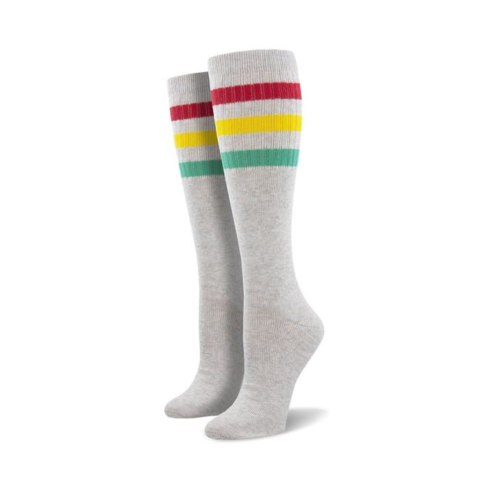 Pair of light blue knee-high socks with a vibrant rainbow striped cuff against a white background.