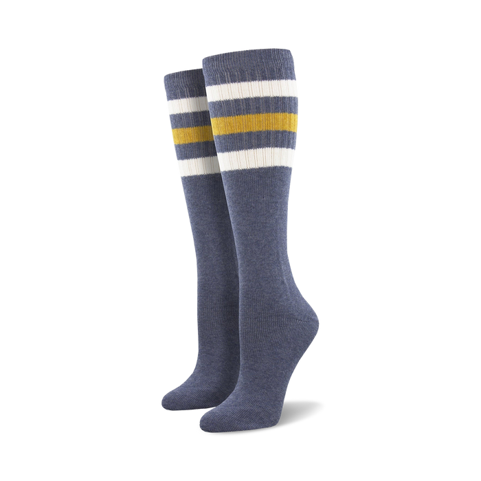 Pair of light blue knee-high socks with a vibrant rainbow striped cuff against a white background.
