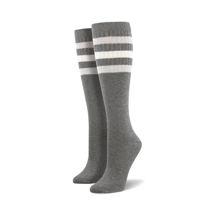Pair of light blue knee-high socks with a vibrant rainbow striped cuff against a white background.