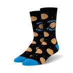 Lifestyle shot of Tough Cookie socks on a person's feet; the socks are black with blue cuffs and chocolate chip cookie designs.
