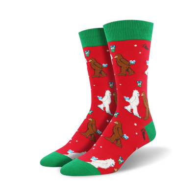 crew length christmas socks in red with cartoonish white abominable snowmen wearing santa hats and carrying gifts on a red background with green snowflakes and a green top.   