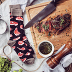 Lifestyle flatlay image showing Prime Cut socks next to a sliced steak, knife, and chimichurri sauce. [lf]