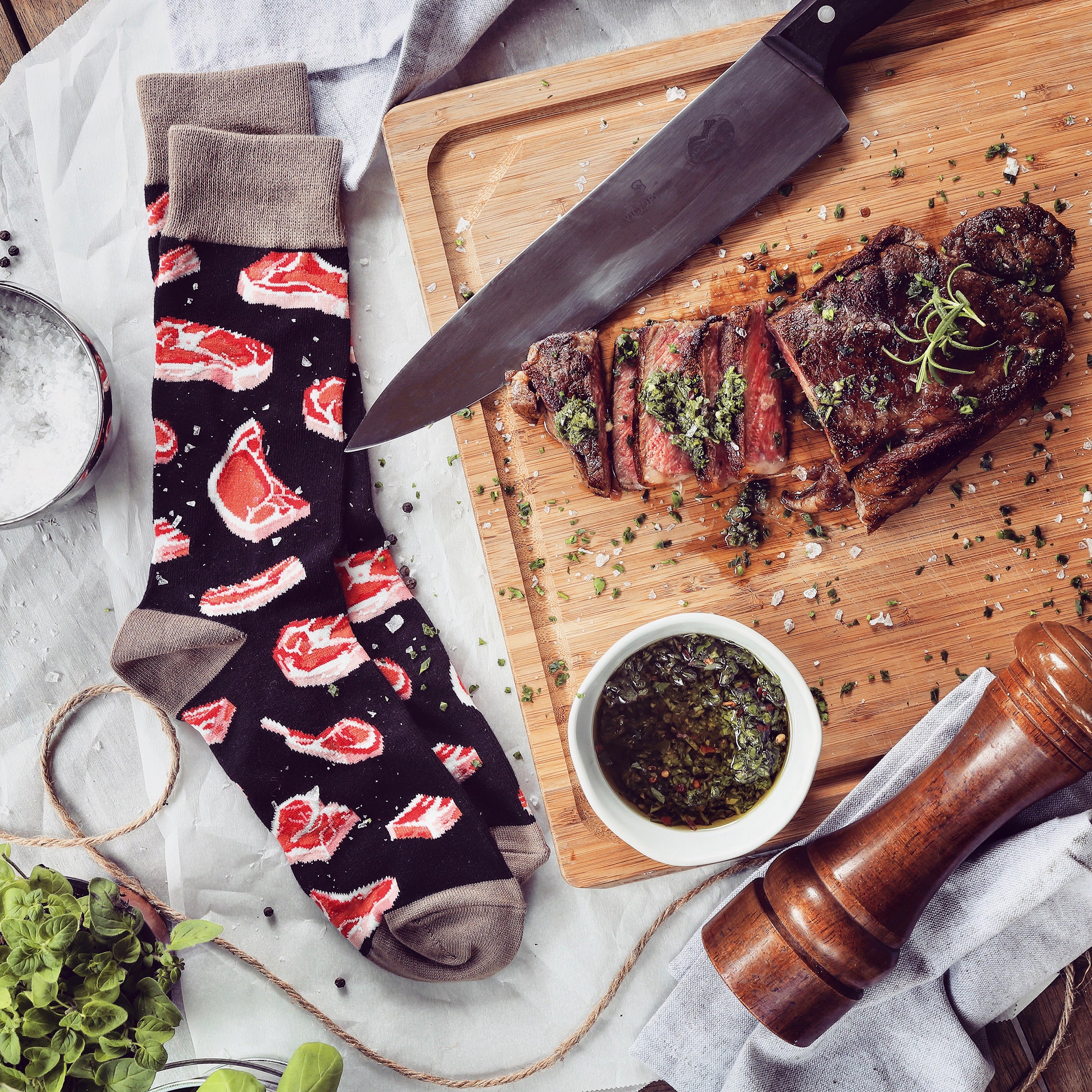 Lifestyle flatlay image showing Prime Cut socks next to a sliced steak, knife, and chimichurri sauce. [lf]