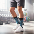 Model wearing teal crew socks with black dumbbells & kettlebells, styled with grey shorts and white sneakers in a gym. [lf]