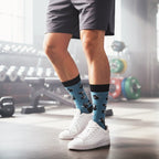 Model wearing teal crew socks with black dumbbells & kettlebells, styled with grey shorts and white sneakers in a gym. [lf]