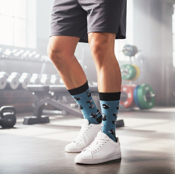 Model wearing teal crew socks with black dumbbells & kettlebells, styled with grey shorts and white sneakers in a gym. [lf]