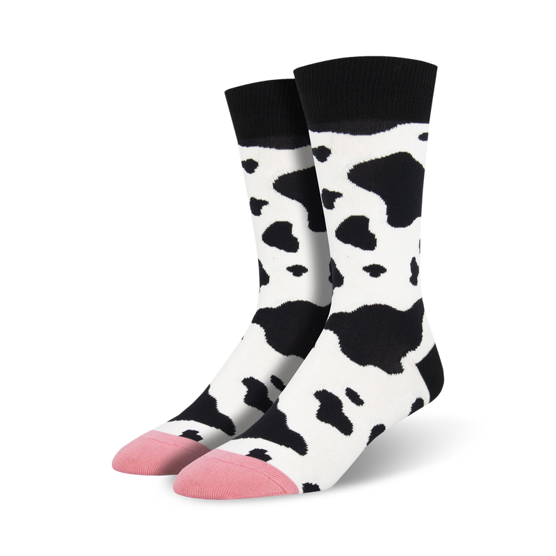 Pair of crew socks with a black and white cow print design.  Pink accents at the toes. Fun and quirky style.