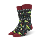 Pair of crew socks, black and green, featuring a Christmas-themed pattern with dinosaurs wearing Santa hats.
