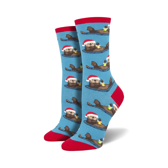 bright blue women's crew socks featuring cartoon otters in santa hats swimming in a light blue sea with red sock tops. perfect for christmas.  