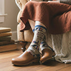 Model wearing brown clogs & a rust dress, showing a tan crew sock with book pattern and 'So many books, so little time' text. [lf]