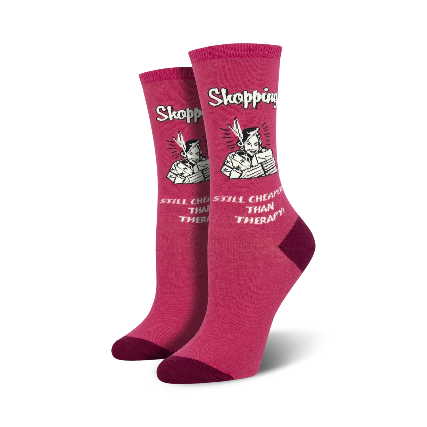 Pair of women's crew socks in pink featuring a retro-style illustration of a woman shopping with the text 'Shopping Still Cheaper Than Therapy'.