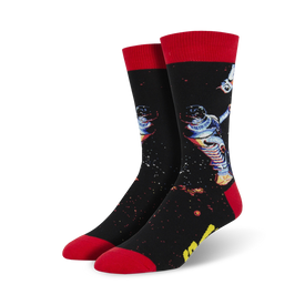 black crew socks with red cuffs and toes feature a pattern of an astronaut floating in space.  