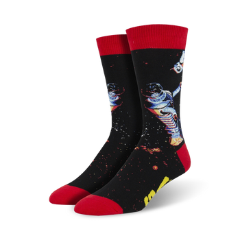 black crew socks with red cuffs and toes feature a pattern of an astronaut floating in space.  