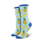 Lifestyle shot showing the light blue 'Partial To Pineapples' socks on a model's feet. The socks' fun design is highlighted.