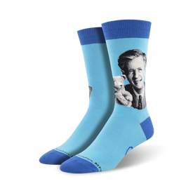 blue mister rogers portrait crew socks for men feature the beloved host in a black suit coat, light dress shirt, and dark tie. he holds a stuffed tiger.  