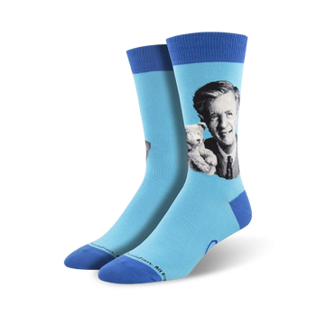 blue mister rogers portrait crew socks for men feature the beloved host in a black suit coat, light dress shirt, and dark tie. he holds a stuffed tiger.  