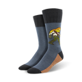 A pair of men's crew socks in blue and tan, featuring a graphic of Bigfoot walking through a mountain range.  The design includes yellow and green accents.